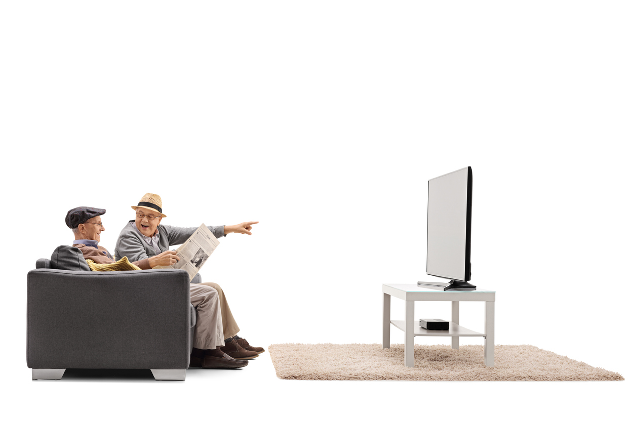 Seniors on a sofa watching television IN THE KITCHEN