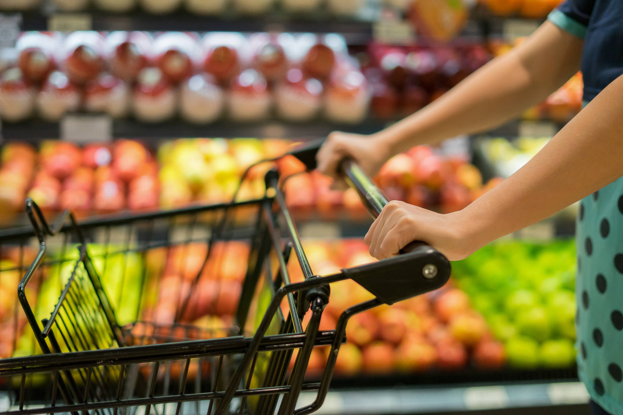 Female Hand Close Up With Shopping Cart in a Supermarket Walking Trough